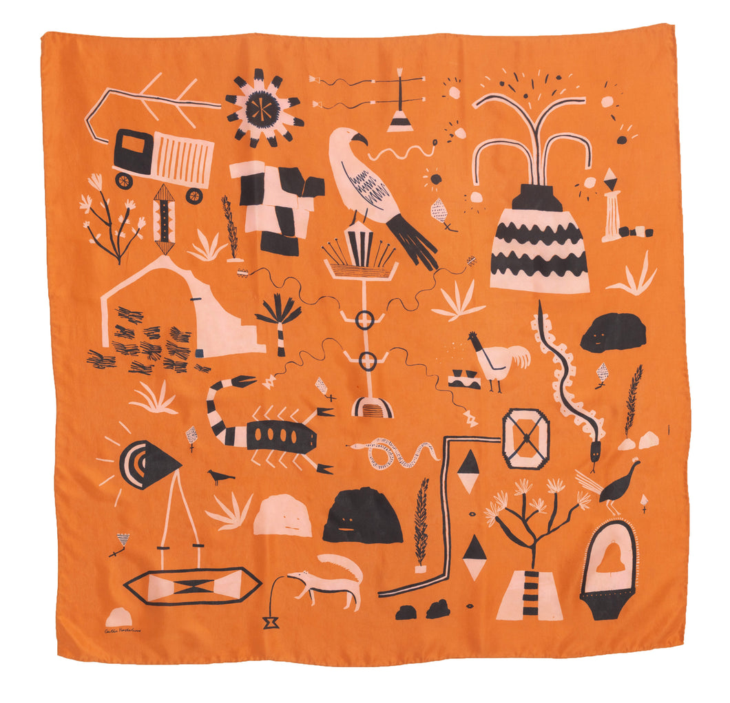 El Sueño Silk Scarf. Orange base colour with pink and navy printed imagery. Imagery depicts animals and ruins with a volcanic landscape.